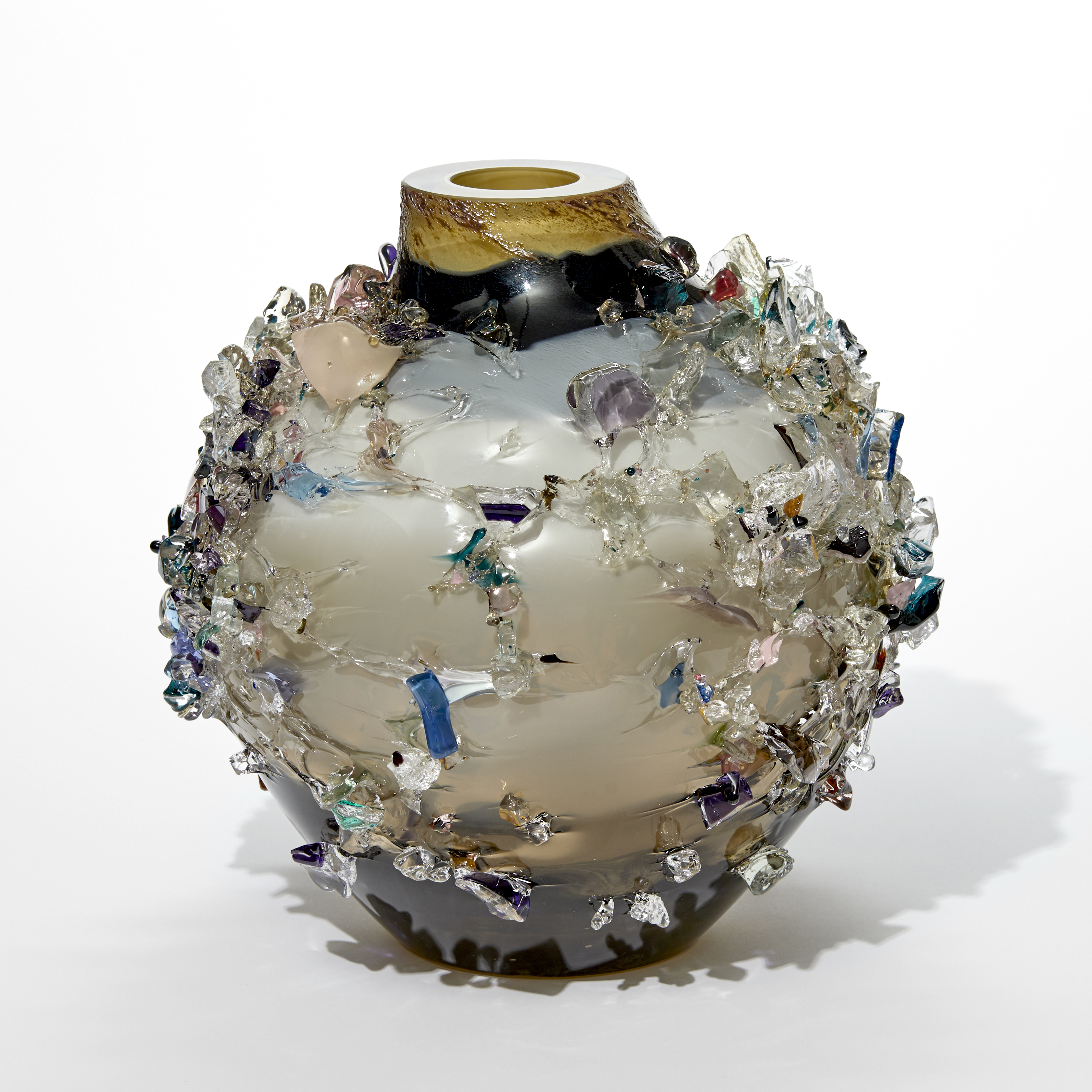 round vase with short wide neck and flat top in dark steel blue grey alabaster and fawn with the exterior covered in organic shards in mixed colours hand made from glass